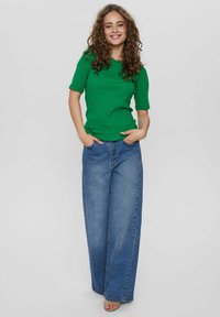 Groen kortmouwtop met een ronde hals, gecombineerd met losse blauwe denim wijdpijpen jeans, met een klassieke vijf-pocket ontwerp.