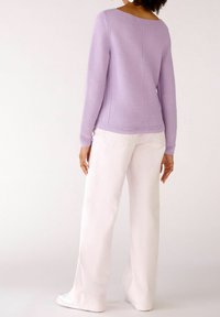 Lilac knit sweater with a boat neck and long sleeves, paired with light pink wide-leg pants, both featuring a smooth texture.