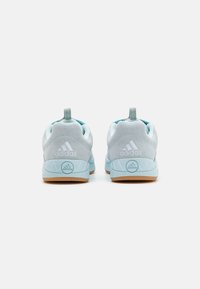 Light blue athletic shoes with a suede upper, textured mesh collar, and rubber sole. Features logo and pull tab at the heel.