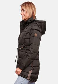 Black puffer jacket with a hood, featuring a cinched waist, quilted texture, brown leather accents, and a logo patch on the sleeve.