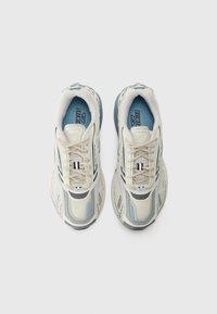 Beige and light blue athletic shoes with mesh and synthetic materials, featuring intricate paneling, laces, and a cushioned sole.