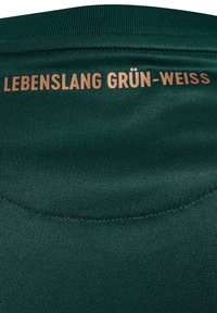 Donkergroene stof met gestikte naad waarop de beige tekst "LEBENSLANG GRÜN-WEISS" vlakbij de bovenrand is gedrukt.