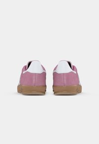 Rosa ruskede sneakers med hvide accenter og en struktureret gummisål. Har en glat bagkamp med tydelige sømme og et lavprofil design.