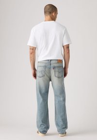 Άσπρο κοντομάνικο μπλουζάκι συνδυασμένο με ανοιχτό μπλε, φαρδιά τζιν παντελόνια με ξεθωριασμένο πλύσιμο και δύο πίσω τσέπες με ετικέτα της μάρκας.