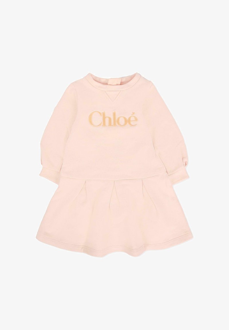 Robe rose clair avec des manches longues, un col rond et une jupe froncée avec des plis ; logo "Chloé" brodé en doré sur la poitrine.