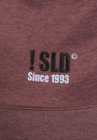 Maroon sweatshirt featuring black and white embroidered text reading "!SLD" and "Since 1993." Text is prominently displayed on the front.