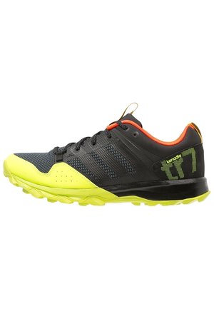 Chaussure de sport noire et jaune néon avec doublure intérieure orange, lacets noirs et semelle texturée, conçue pour la course en sentier ou les sports de plein air.
