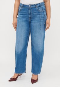 Light blue, wide-leg jeans with a high waist, featuring a button and zipper closure. The fabric has slight fading and accompanied by a tie detail.