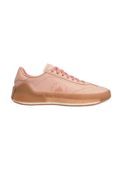 Peach-colored athletic shoes with a smooth leather upper, matching laces, and a textured rubber sole featuring a logo on the side.