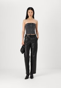 Top corset noir sans bretelles avec un design structuré, associé à un pantalon en cuir noir à coupe décontractée et des bottines noires à talons.