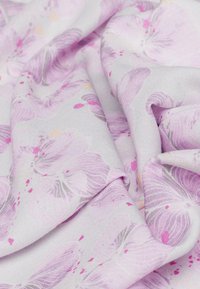 Lichtgrijze stof met een bloemenpatroon in roze en lavendeltinten, met een zachte textuur en subtiele kleuraccenten.