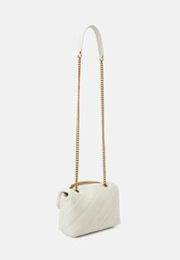 Weiße Lederhandtasche mit Zickzackstich, ausgestattet mit einem kurzen Ledergriff und einem goldenen Kettenriemen. Kompaktes Design mit einer runden Form.