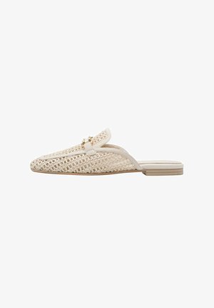 Beige geweven instapschoenen met een platte zool, voorzien van een decoratief gouden hardware detail op het bovenwerk en een gladde, lederachtige bies.