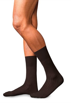 Calcetines marrones acanalados con una textura suave, que presentan un puño grueso. El diseño incluye sutiles líneas verticales para un detalle adicional.