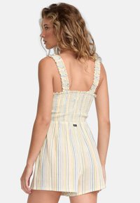 Frynset stropper, smocket bodice og stribet stof i pastelfarver. Beklædningen har en afslappet pasform med et mærke på bagsiden.