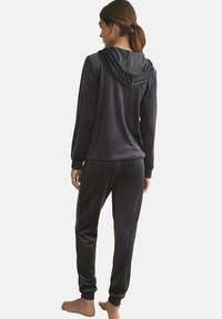 Zwarte, zachte velours hoodie en joggers set met een gathered capuchon. Heeft ribgebreide manchetten en een halslijn; gladde textuur, fitted stijl.