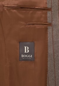 Interno in satin marrone con due tasche orizzontali. Etichetta attaccata con la scritta "BOGGI MILANO" e una lettera 'B' stilizzata in bianco. Bordo in tessuto grigio.