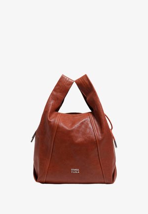 Brūnas ādas rokassoma ar unikālu skulpturālu formu, kas aprīkota ar diviem augšējiem rokturiem un zīmola logo priekšpusē.