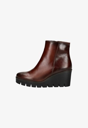 Bottines en cuir marron avec un design épuré, un bout arrondi et un talon compensé. Présentent une semelle en caoutchouc noir texturé. Fermeture éclair sur le côté.
