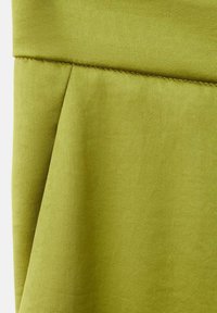 Tejido verde oliva con una textura suave, que presenta costuras cosidas y un diseño plisado, destacando su caída suave y forma.