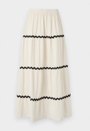 Jupe longue à volants en tissu crème avec des bords ondulés noirs. Dotée d'une taille élastique pour plus de confort et d'un tomber fluide et léger.