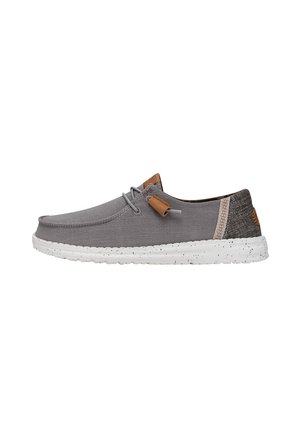 Gray canvas shoes with a low-profile design, featuring a textured fabric upper, white speckled sole, and brown leather accents.