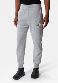 Grijze sweatpants van zachte stof, met een elastische tailleband, taps toelopende pijpen en een zwart logo op de linkerdij.
