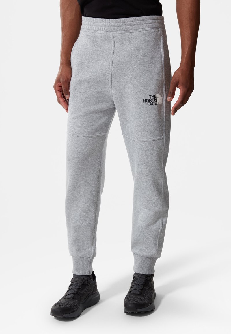 Grijze sweatpants van zachte stof, met een elastische tailleband, taps toelopende pijpen en een zwart logo op de linkerdij.