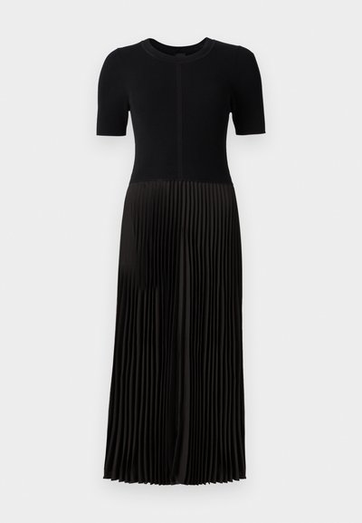 Robe noire avec un haut côtelé et une jupe plissée. Manches courtes et encolure ronde. Le matériau semble doux avec une texture lisse.