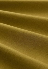 Stof de culoare verde măsliniu, cu o textură netedă, având secțiuni pliate care evidențiază senzația sa moale, asemănătoare bumbacului și culoarea uniformă.
