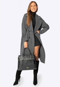 Cappotto di lana grigio con design doppiopetto, borsa in pelle nera con zip frontale e stivali alti neri in suede fino al ginocchio.