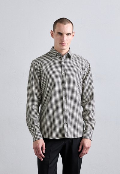 Chemise à carreaux noire et blanche avec manches longues, col évasé et coupe ajustée. Tissu lisse avec une texture subtile.