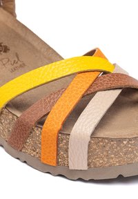 Sandale en cuir avec des sangles jaunes, oranges, brunes et beiges au fini texturé. Semelle intermédiaire en liège et semelle extérieure en caoutchouc.