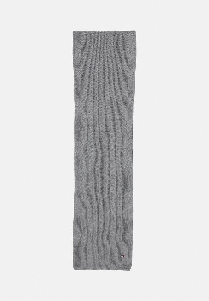 Cachecol cinza tricotado, em forma retangular, com textura canelada, apresentando um pequeno logotipo no canto. Tecido suave, com distribuição de cor uniforme.