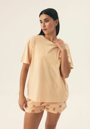 Peach-colored cotton t-shirt with short sleeves, featuring a small floral design, paired with matching shorts adorned with a fruit pattern.