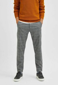 Gray plaid pants with a slim fit, featuring a checkered pattern. Made of soft fabric, styled with a tapered leg and side pockets.