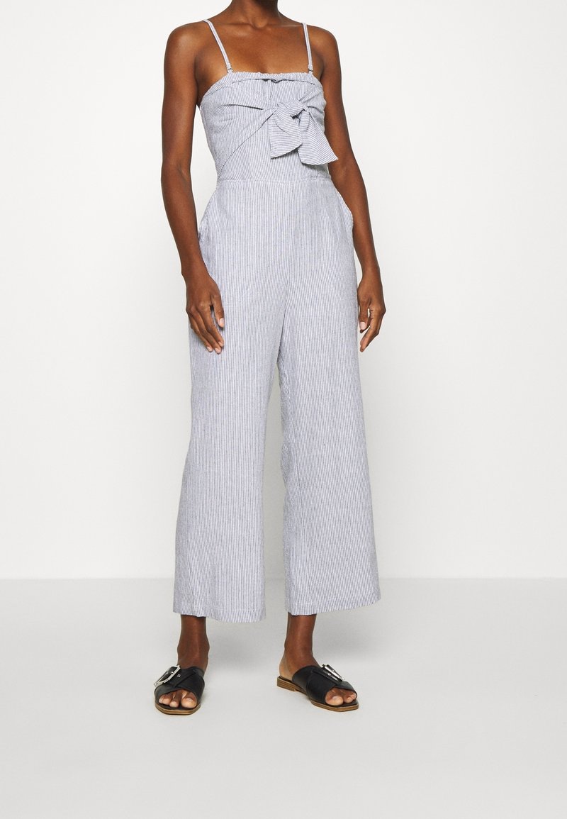 Gestreepte jumpsuit met een strikdetail aan de voorkant, wijde pijpen en dunne banden. De stof lijkt licht en ademend. Accessoires zijn niet inbegrepen.