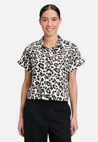 Cropped button-up shirt in a leopard print pattern: cream base with black and tan spots. Features short sleeves and a collared neckline.