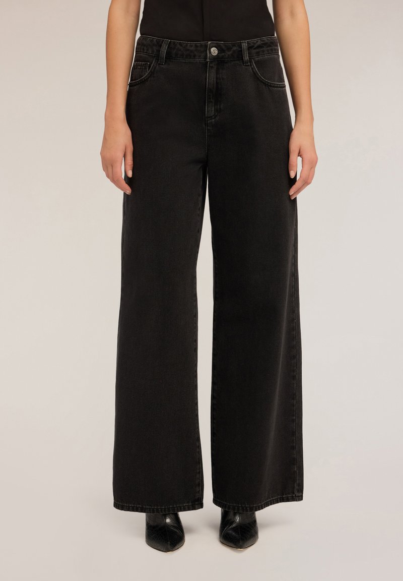 Schwarze Jeans im weit geschnittenen Design mit klassischem Fünf-Taschen-Stil, Metallknopfverschluss und leicht verblichenem Material.