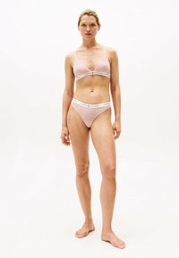 Lichtroze gestreept lingeriesetje met een driehoekige bralette en bijpassende string. Bevat een logo band en een minimalistisch ontwerp, gemaakt van zachte stof.