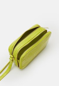 Borsa in pelle verde con stampa coccodrillo, dotata di due scomparti con zip, caratterizzata da accessori in tono oro e tracolla rimovibile.