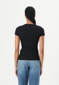 Black short-sleeve t-shirt with a fitted design, made of smooth fabric. Plain back view, paired with light blue denim jeans.
