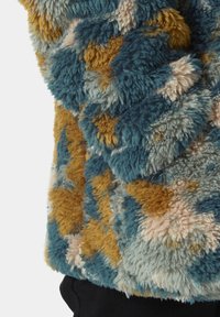 Maglione in pelliccia sintetica color teal, senape e crema con una superficie morbida e texturizzata. Il design presenta un motivo astratto e un colletto rotondo.