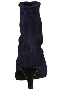 Bottines en cuir suédé bleu marine avec un talon effilé, texture lisse et détails cousus. Tissu doux épousant la forme de la cheville.