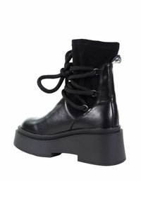 Czarne botki za kostkę o gładkim skórzanym wykończeniu, z teksturowanym zamszowym kołnierzem i masywną podeszwą. Posiadają czarne sznurowanie z przędzy i metalowe akcenty.