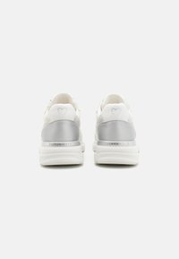 White sneakers with a shiny silver heel accent, textured upper, and embossed heart detail on the heel. Features a cushioned sole.