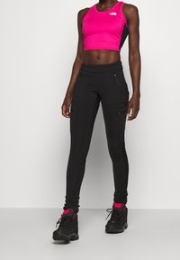 Tajta svarta cargo-byxor med flera fickor, kombinerat med en ljusrosa kortärmad sporttopp. Strukturerad tyg med elastiska detaljer vid ärmsluten.