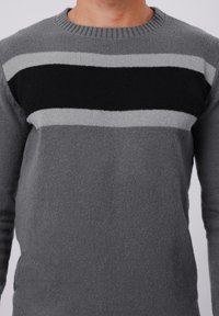 Gray knitted sweater featuring horizontal stripes in dark gray, light gray, and black across the chest. Round neckline, textured fabric.