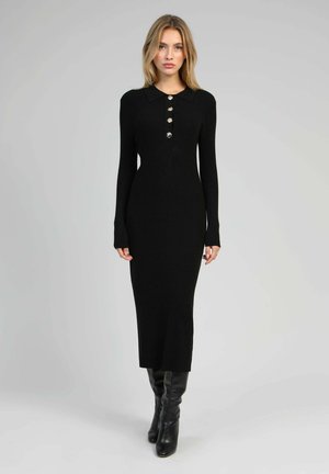 Robe tricotée noire à manches longues avec un col, comportant cinq boutons métalliques sur le devant, coupe ajustée et longueur jusqu'à la cheville.