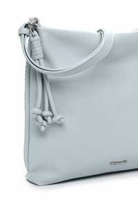 Gaiši zilas krāsas ādas plecu soma ar teksturētu virsmu, kas rotāta ar sasienamu akcentu un sudraba krāsas logotipu, mīksti noapaļotas formas.